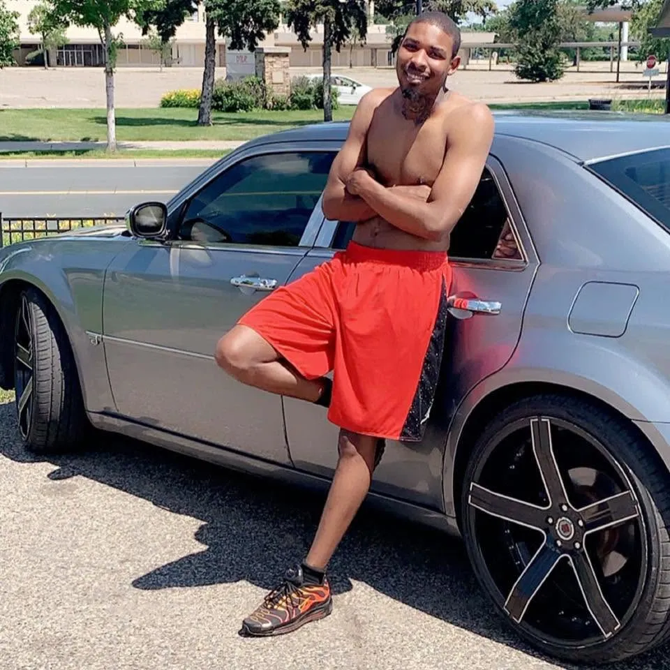 Carlton Johnson, Minneapolis shooting suspect, posing by a gray car.