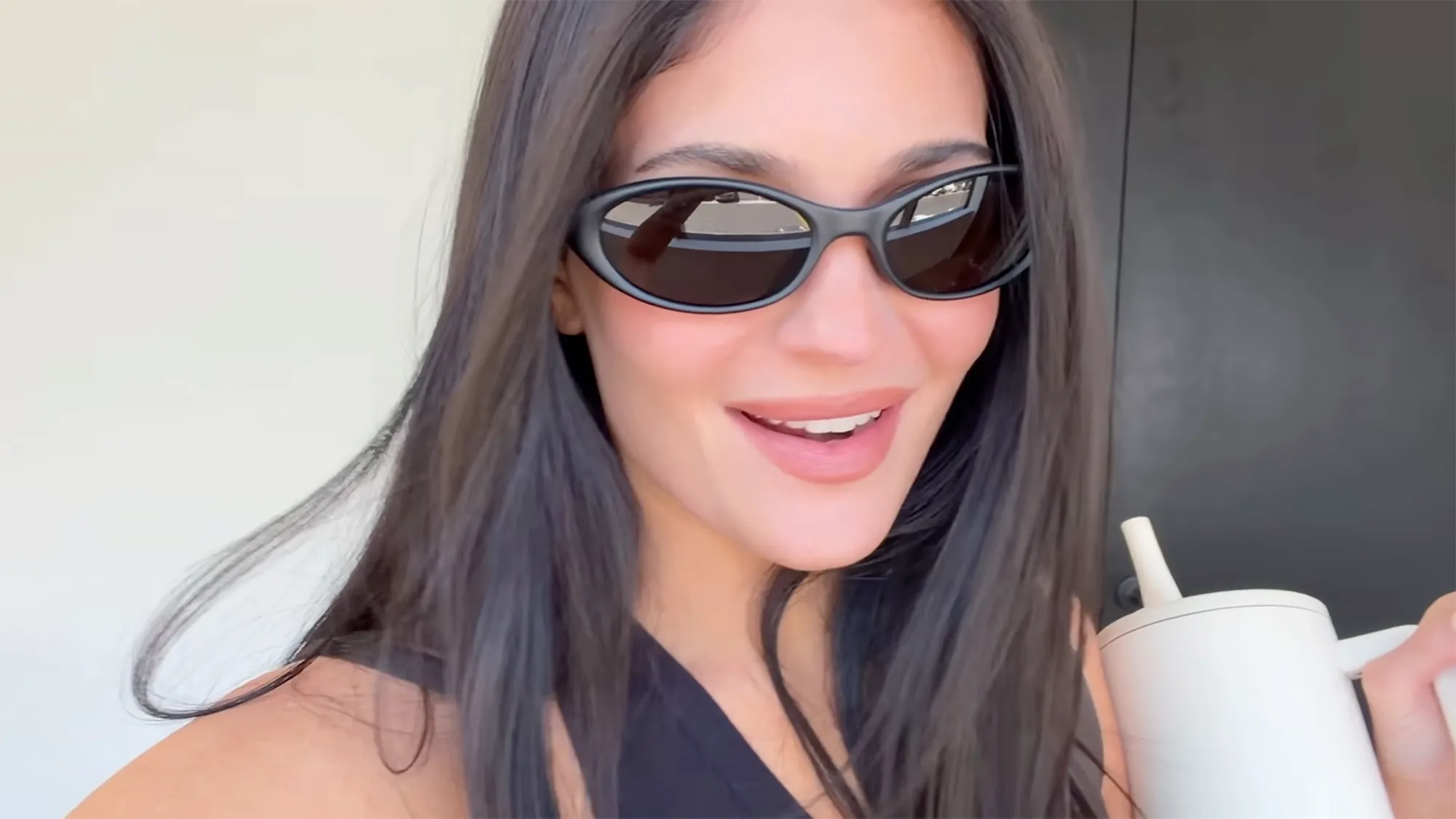 Kylie Jenner wearing sunglasses and holding a cup with a straw.