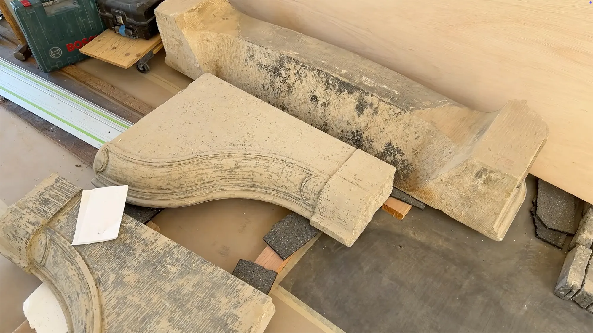 Construction materials, including large decorative stone pieces and tools, on a floor.