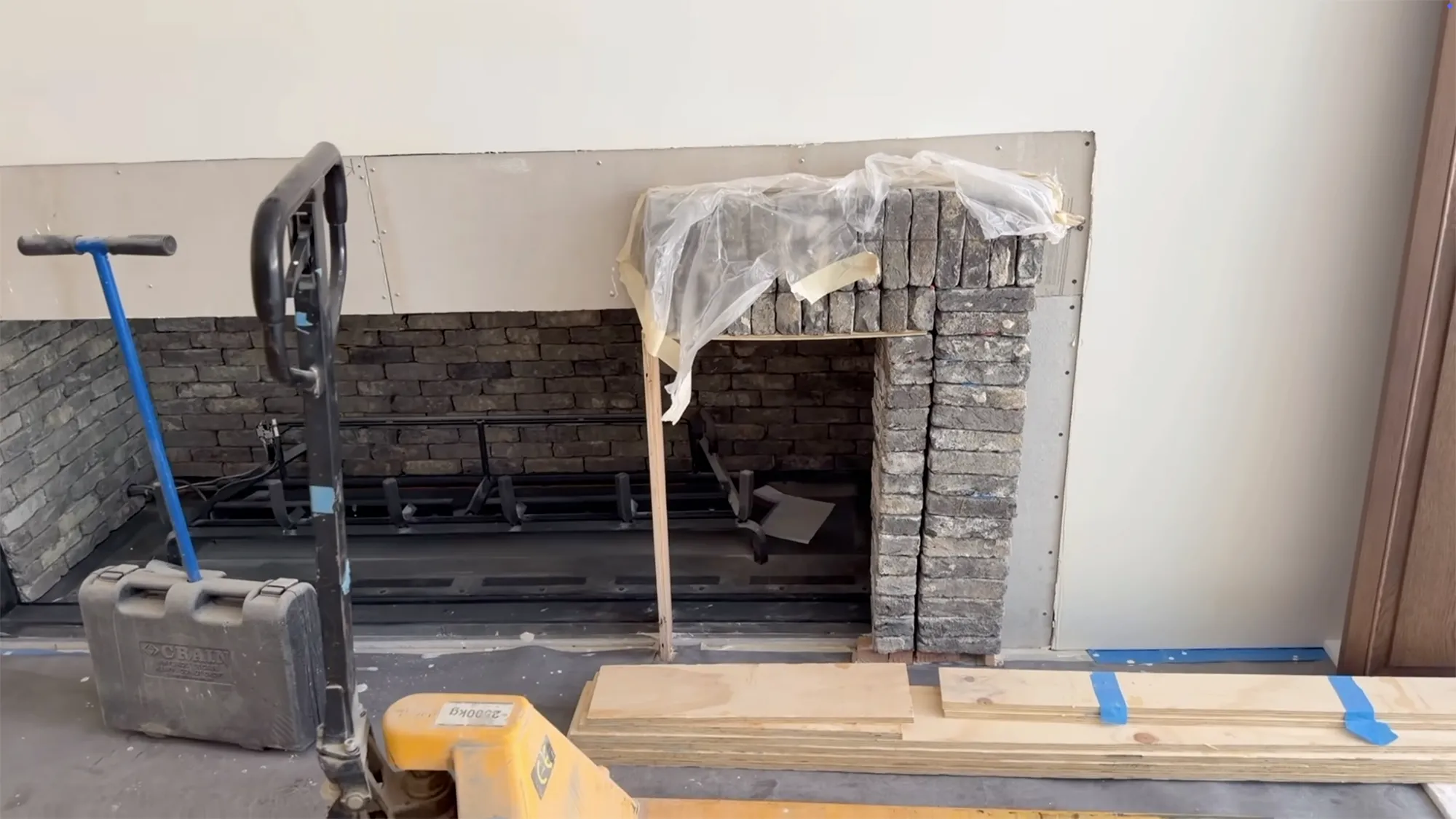 The interior of Kylie Jenner's new home under construction, showing a fireplace opening made of dark stacked stone.