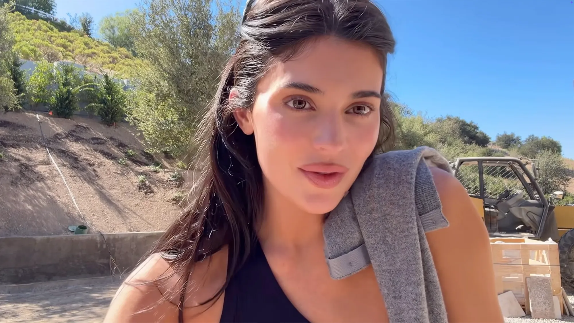 Kylie Jenner at her new home, which is under construction, with a grey towel on her shoulder.