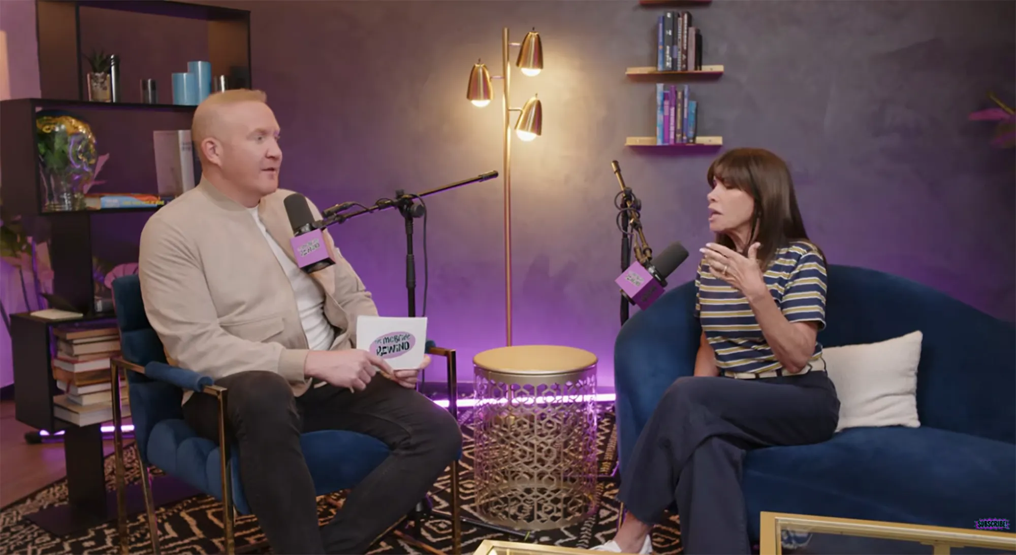 A man and a woman speaking into microphones in a podcast studio.