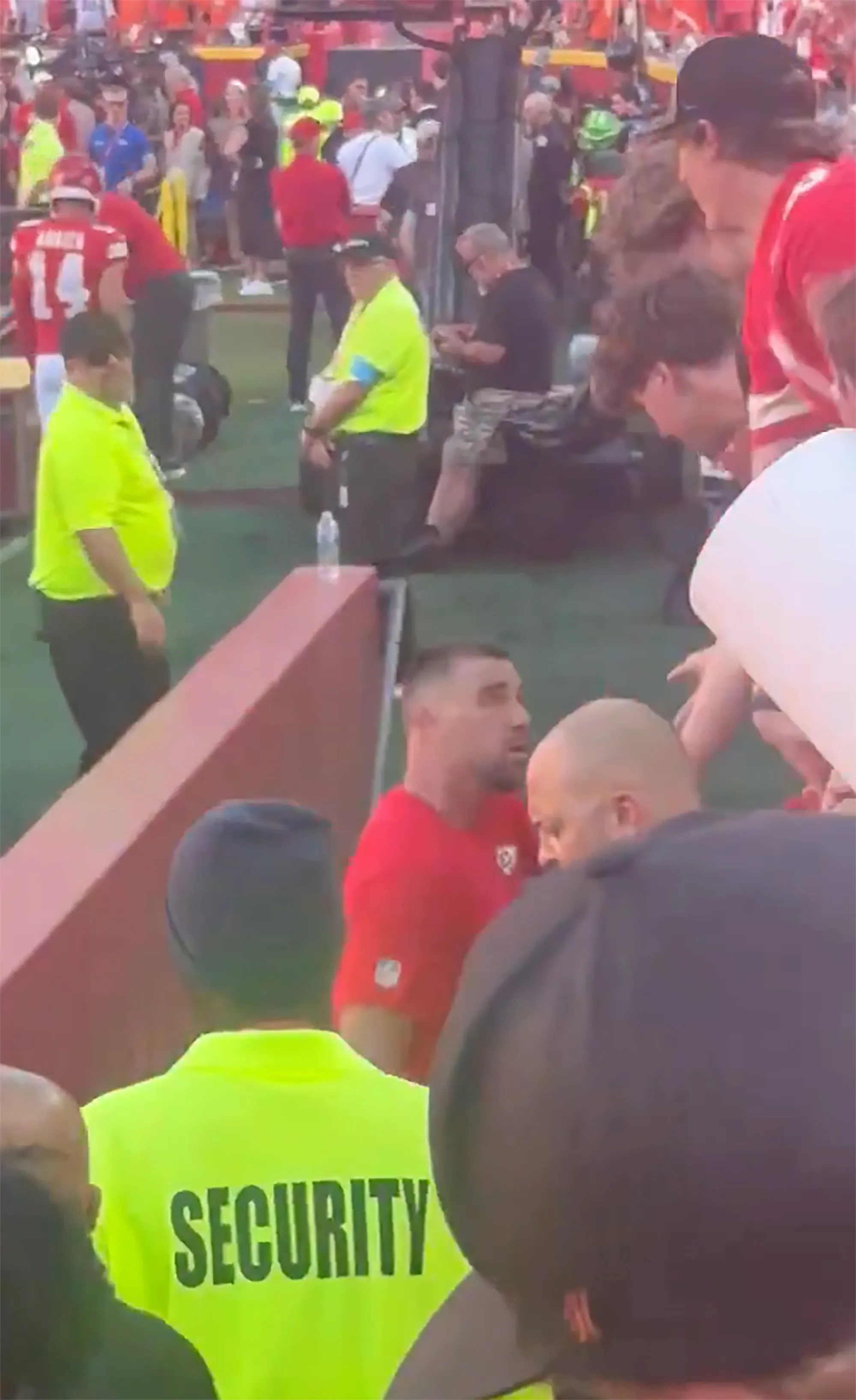 Travis Kelce being escorted off the field by security during a game.