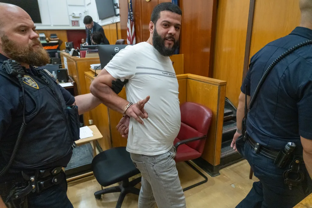 Yehia Amin in handcuffs, being escorted by police.