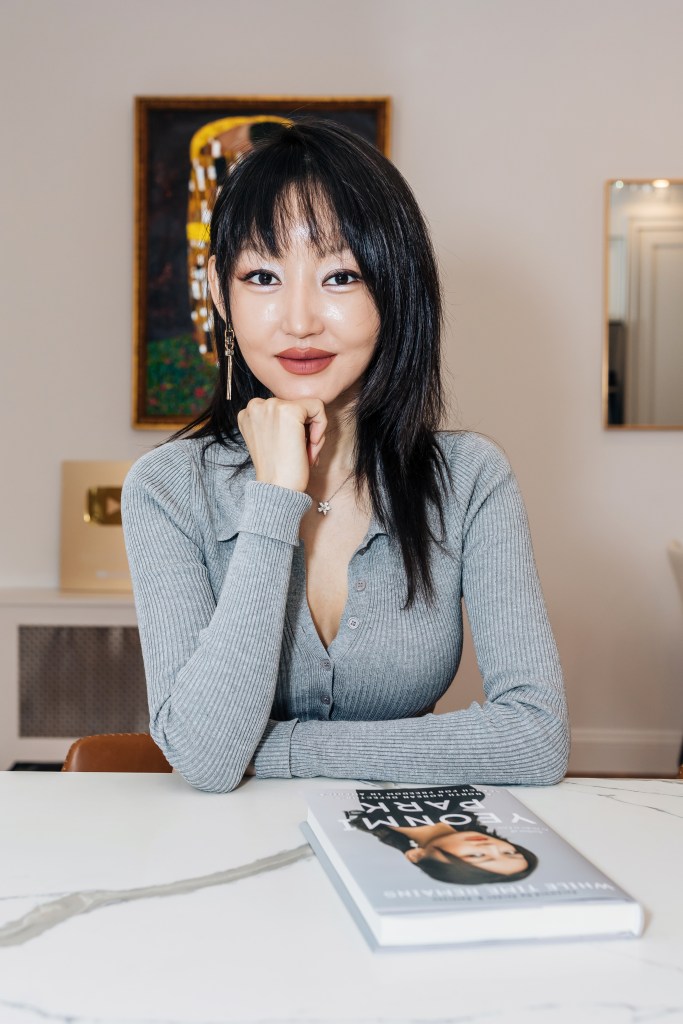 Yeonmi Park seated at a table with her book