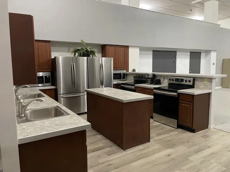 Kitchen units with stainless steel appliances, including several refrigerators, stoves, and microwaves.