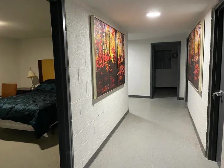 A concrete hallway in a bunker with bedrooms and art on the walls.