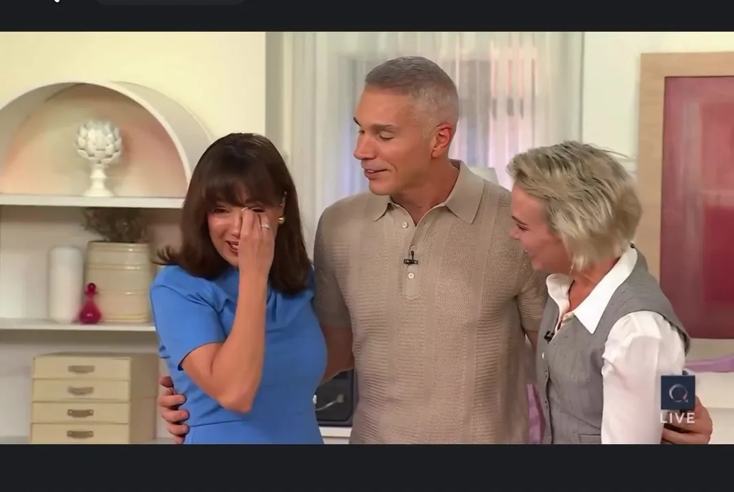 QVC host Sandra Bennett wiping away tears while two co-stars stand beside her.