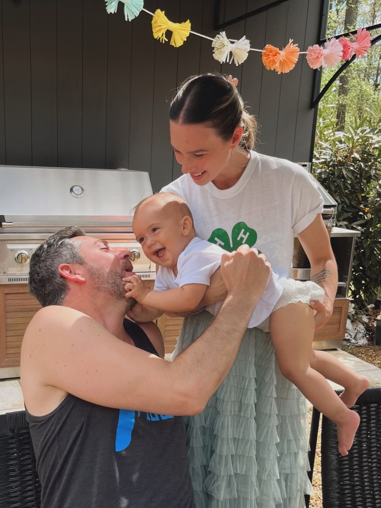 Zachary Levi and Maggie Keating play with their son Henson Ezra Levi Pugh in an outdoor setting.