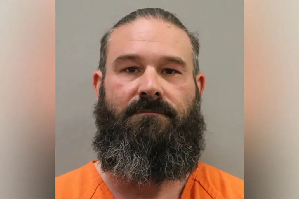 Mugshot of a bearded man in an orange jumpsuit.