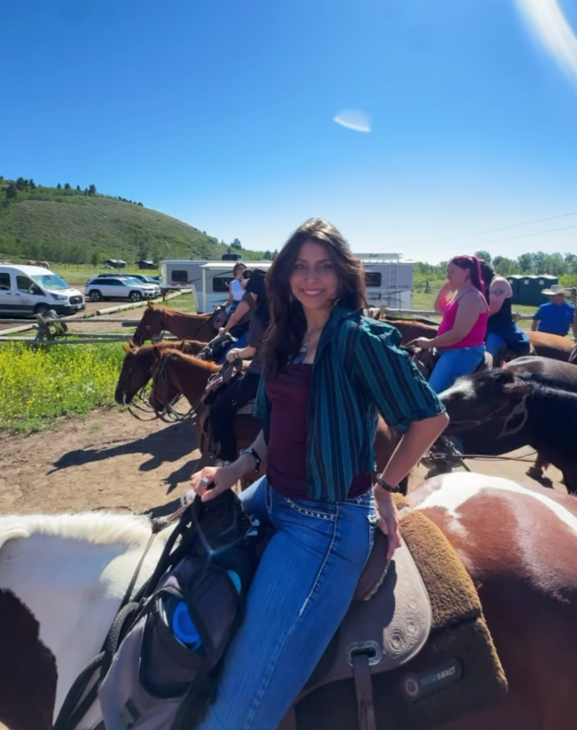 Zoe De La Paz smiling while sitting on a horse.