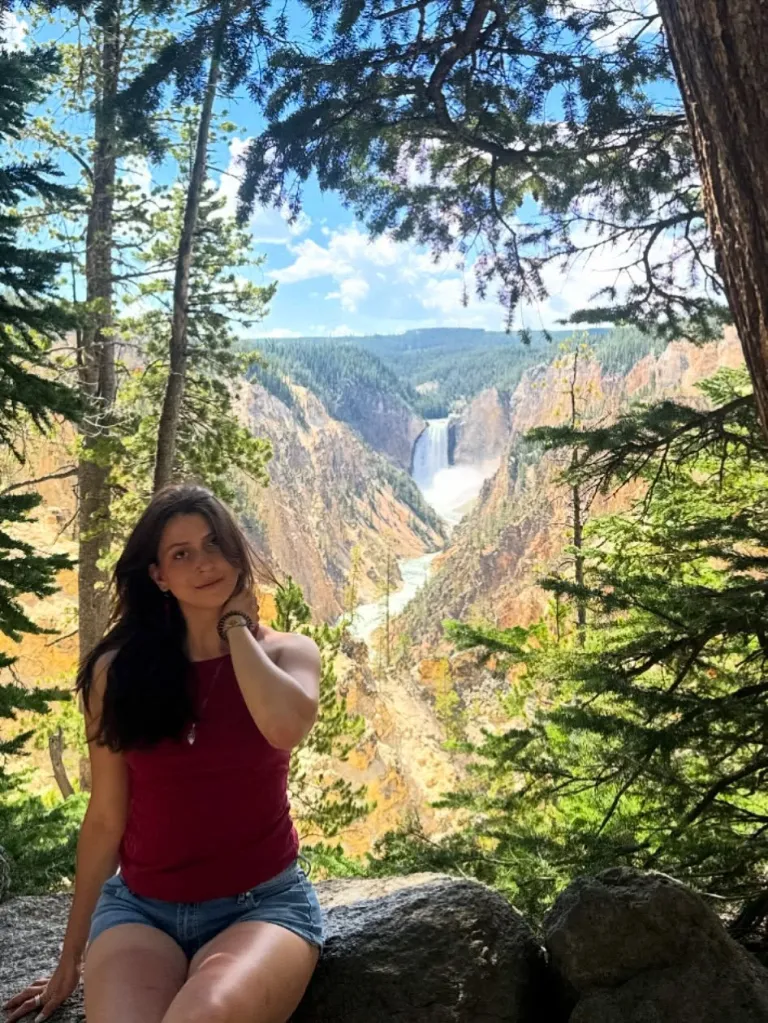 Zoe De La Paz sitting in front of a waterfall in a canyon.