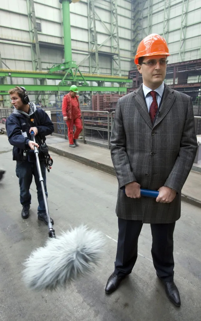 Vitaly Yusufov, owner and director of Nordic Yards, in a shipbuilding shed, with a sound technician holding a boom mic in the background.