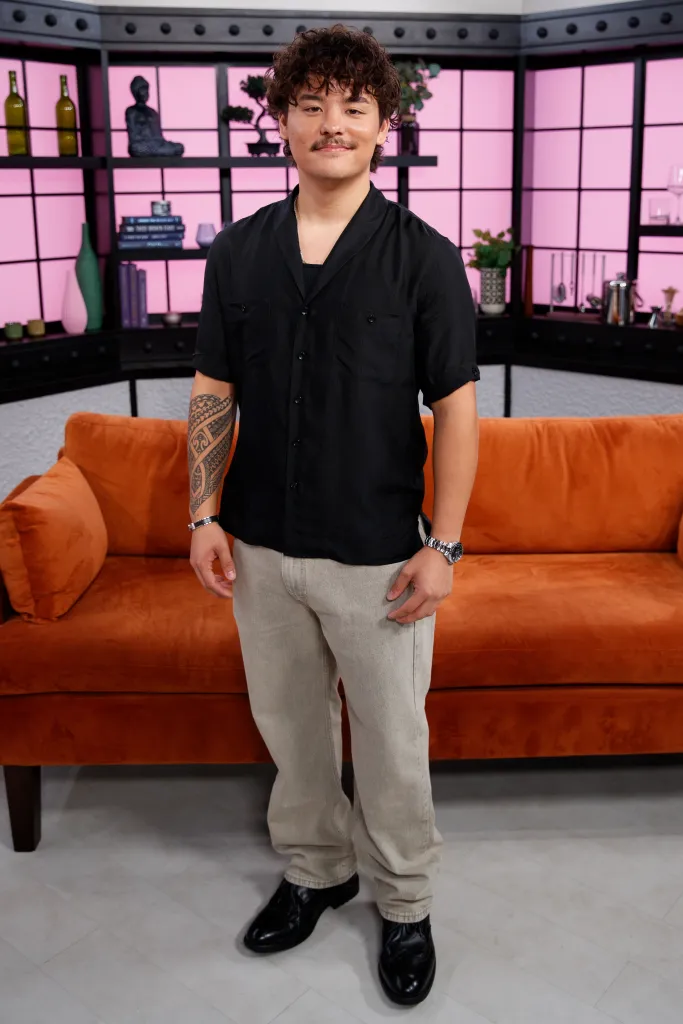 Collin Gosselin standing in front of an orange couch in a studio setting.