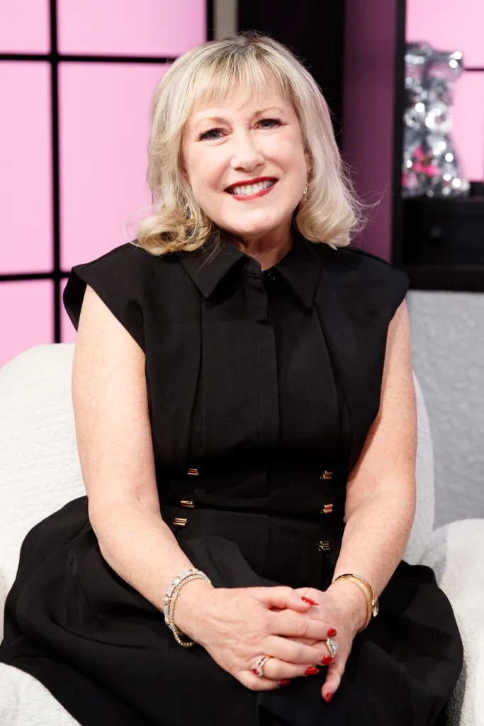 Cathy Nesbitt smiling while sitting on a white armchair during an interview.