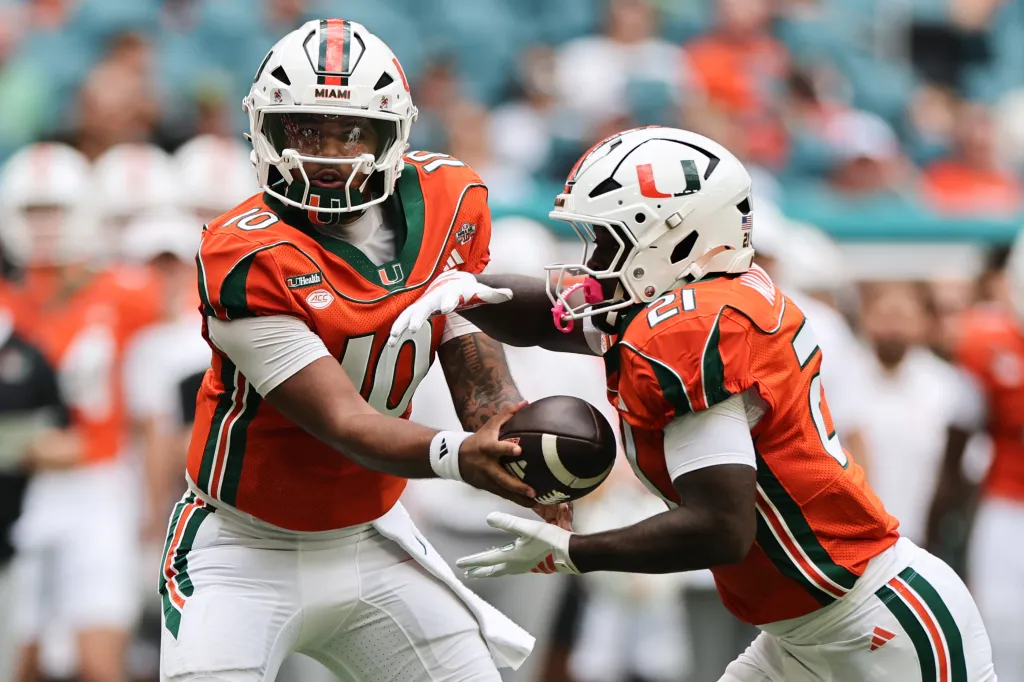 Miami Hurricanes quarterback Darian Mensah hands off the ball to running back Javian Mallory during a game against the Pittsburgh Panthers.