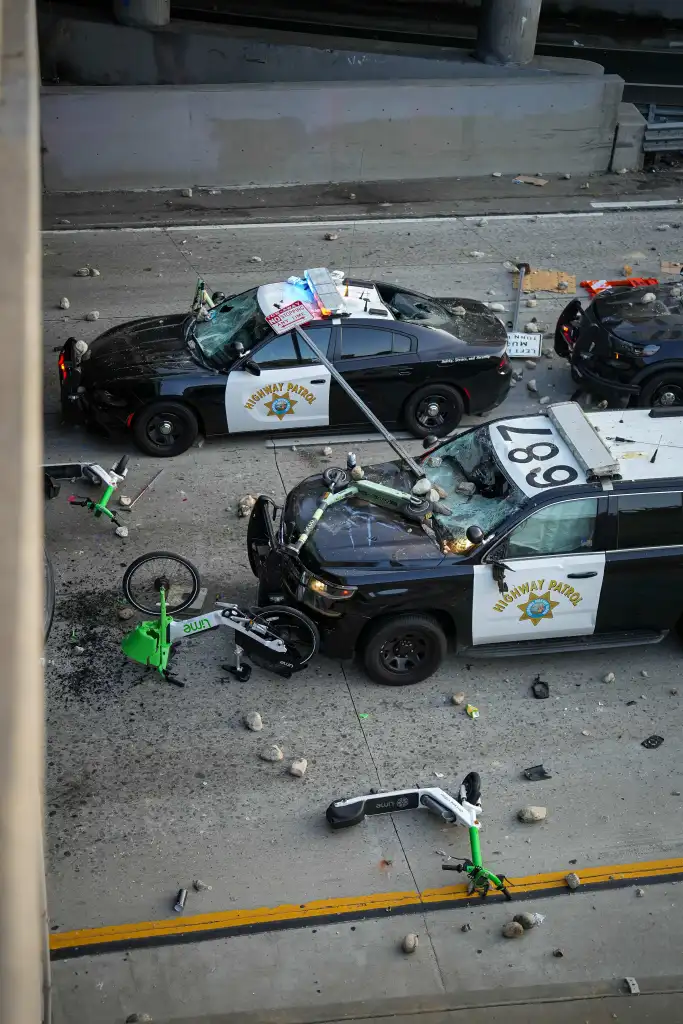 Damaged California Highway Patrol vehicles sit amid rocks, Lime scooters and other debris on a freeway following protests in downtown Los Angeles.