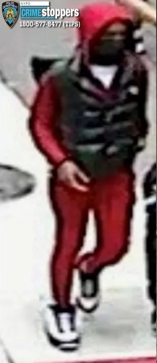 Surveillance photo of a suspect wanted in connection with a homicide, wearing a red tracksuit, black vest, and face mask.
