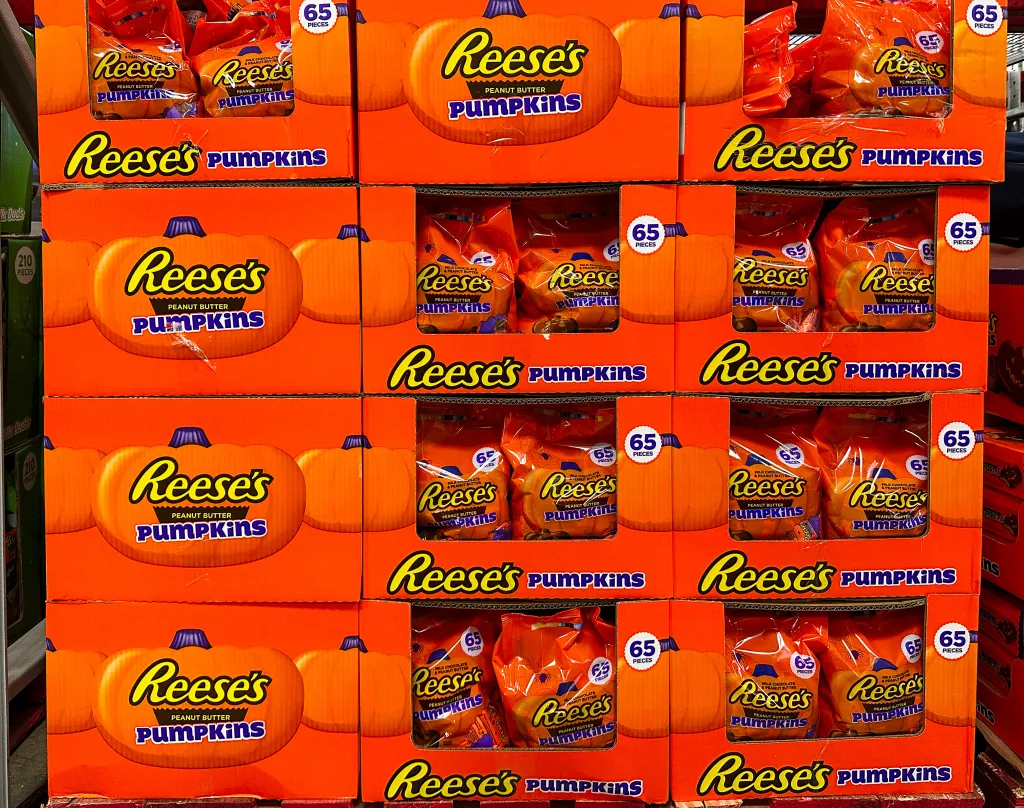 Stacked cardboard boxes of Reese's Peanut Butter Pumpkins Halloween candy in a store.