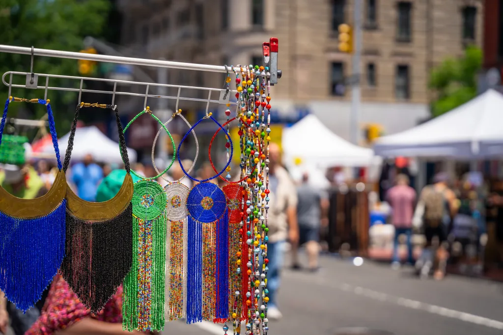 Beaded jewelry hanging on display at a street fair.