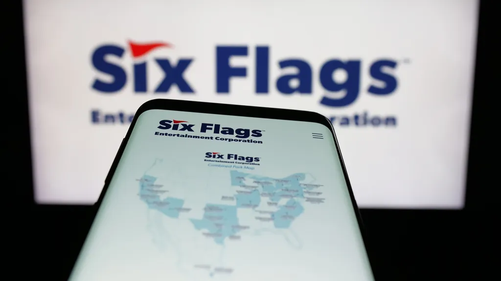 Mobile phone displaying the Six Flags Entertainment Corporation website in front of the company logo.