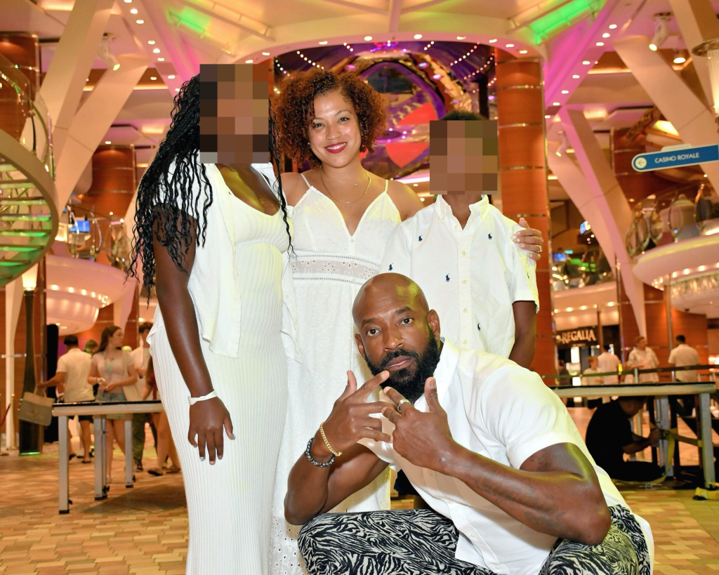 A family of five, all dressed in white, poses on a cruise ship.