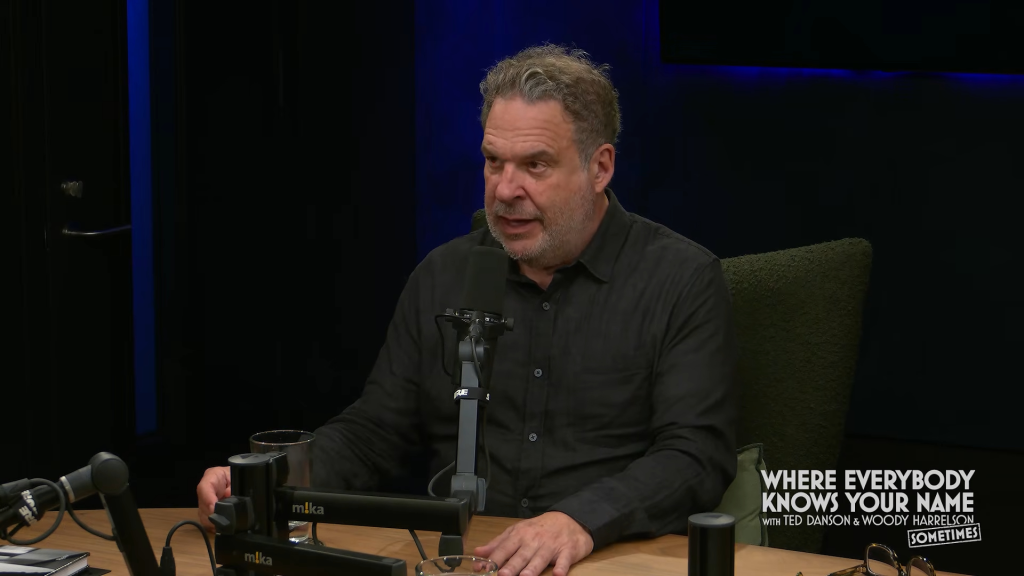 Jeff Garlin speaking into a microphone on a podcast set.