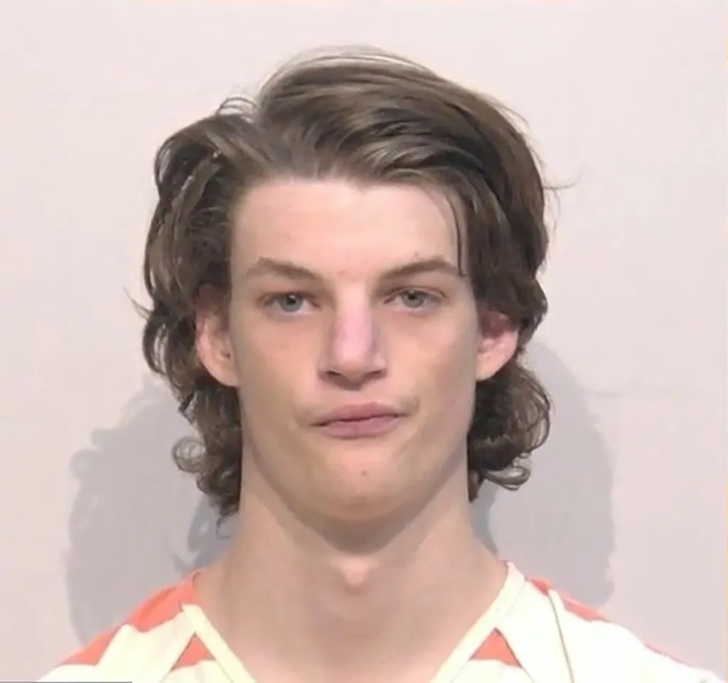 A teenager with dark hair in a mugshot