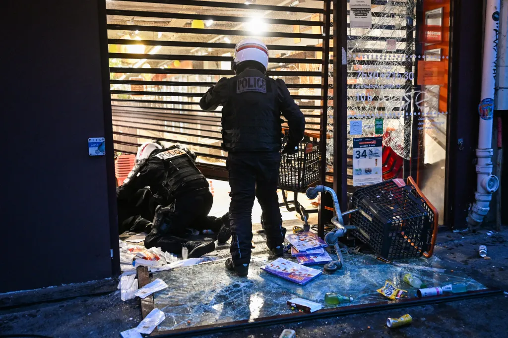Police officers detain a person at a ransacked Franprix store during a demonstration in Paris.