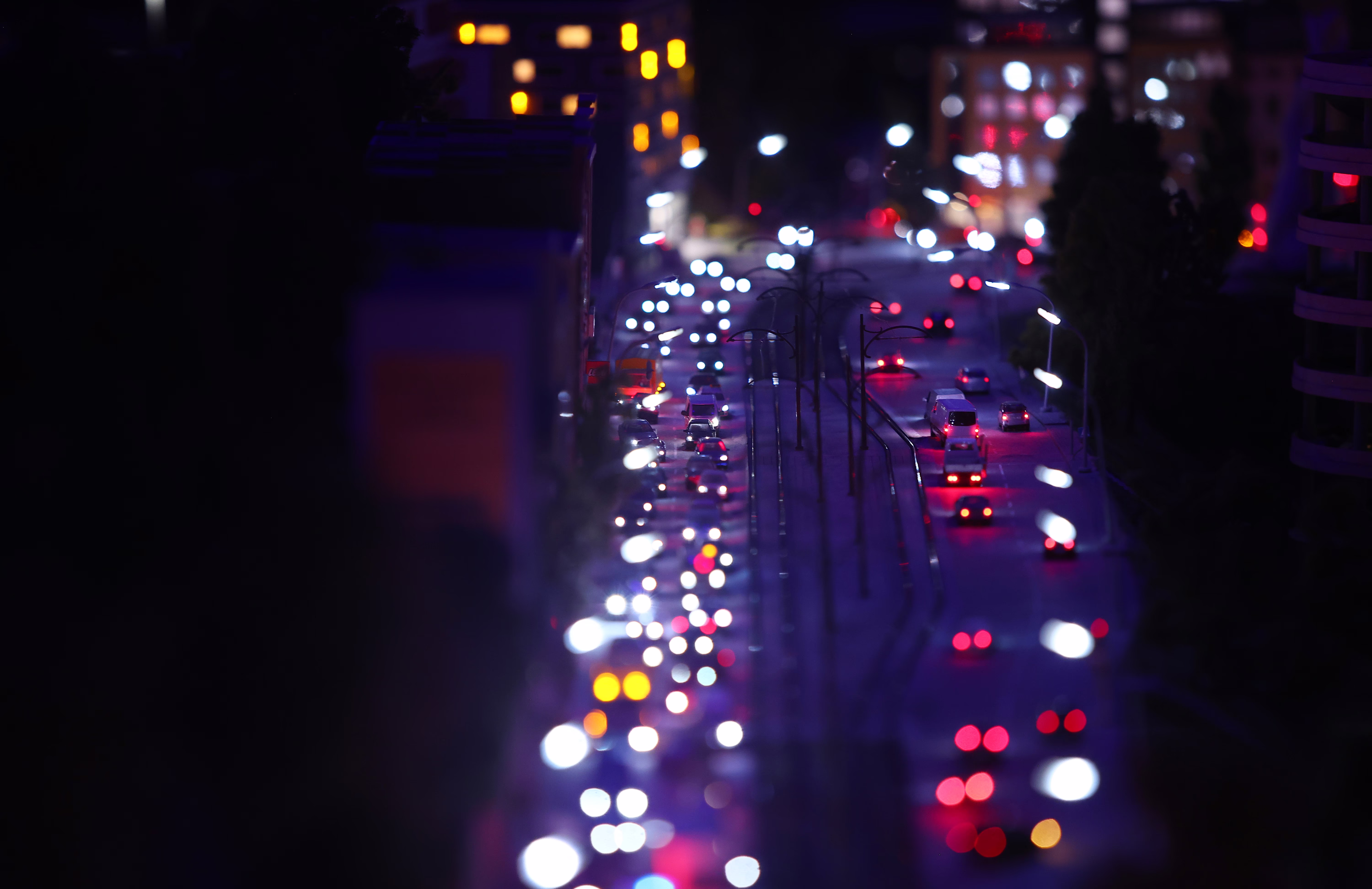 A miniature scene of traffic on a city street, lit up in the dark