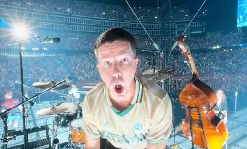 Zach Bryan's drummer on stage in front of a large crowd, wearing a jersey with special meaning.
