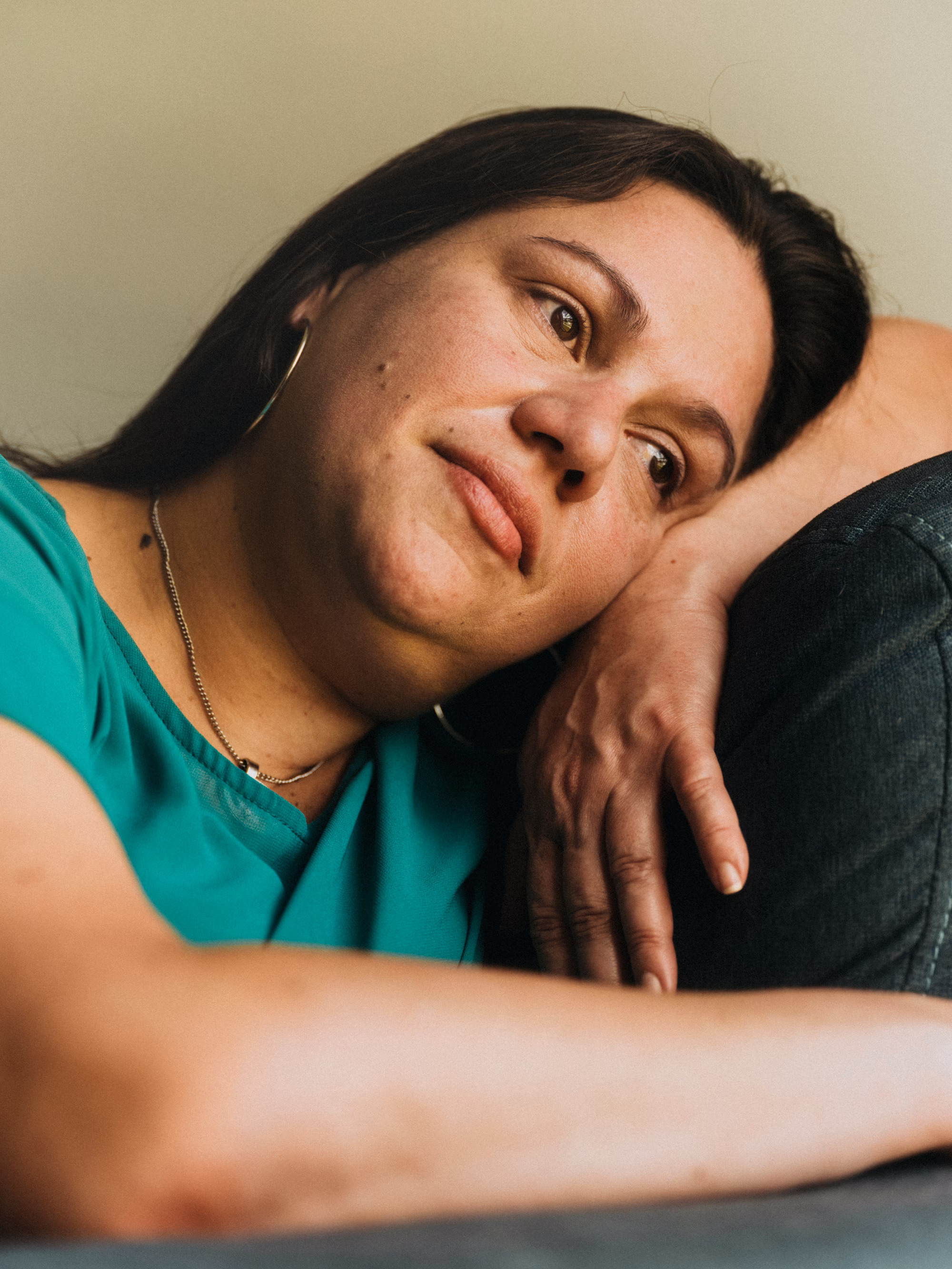 photo of woman with dark hair resting her head on her arm draped across a sofa