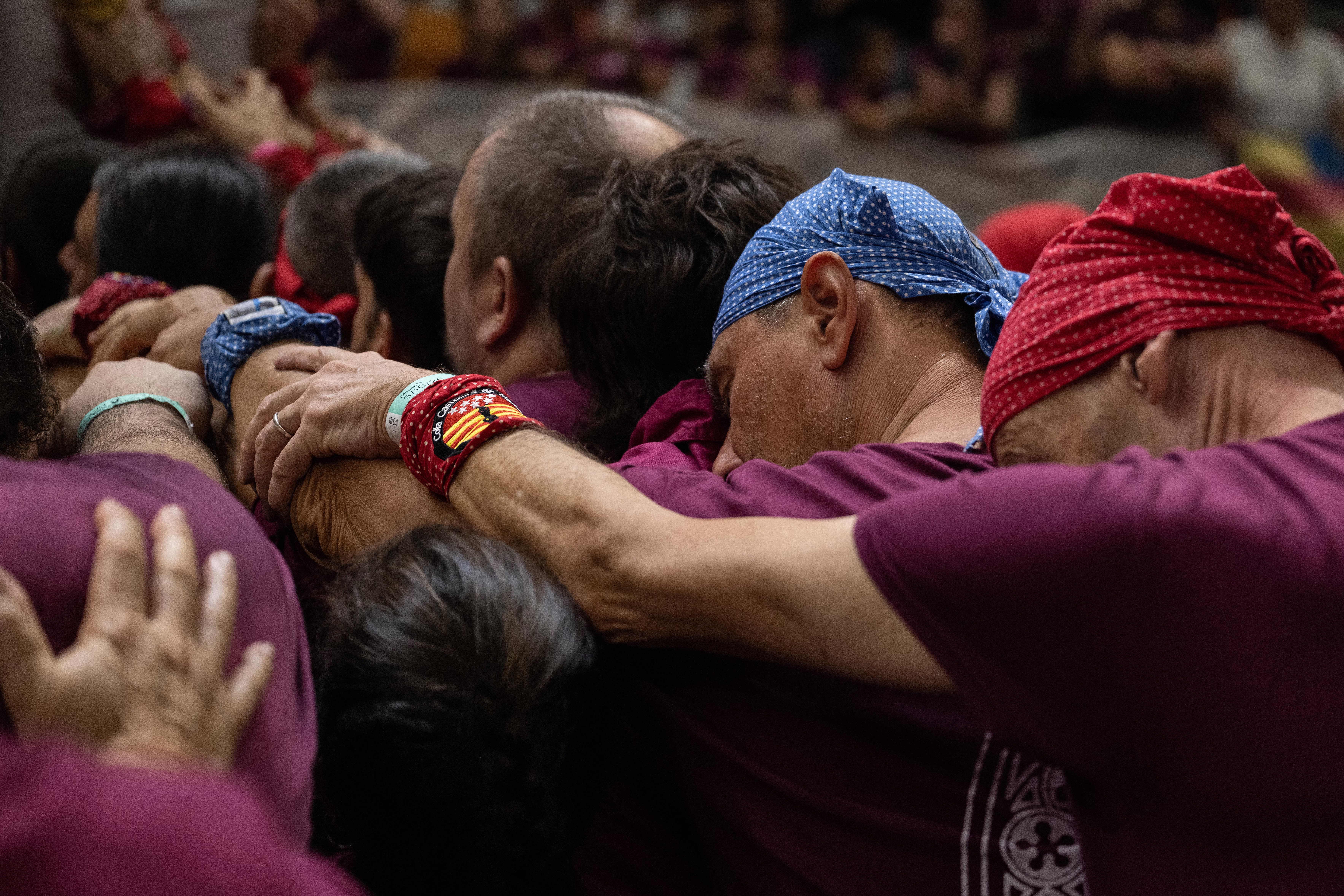 A close view of part of a larger group of people leaning on each other, supporting an unseen human tower