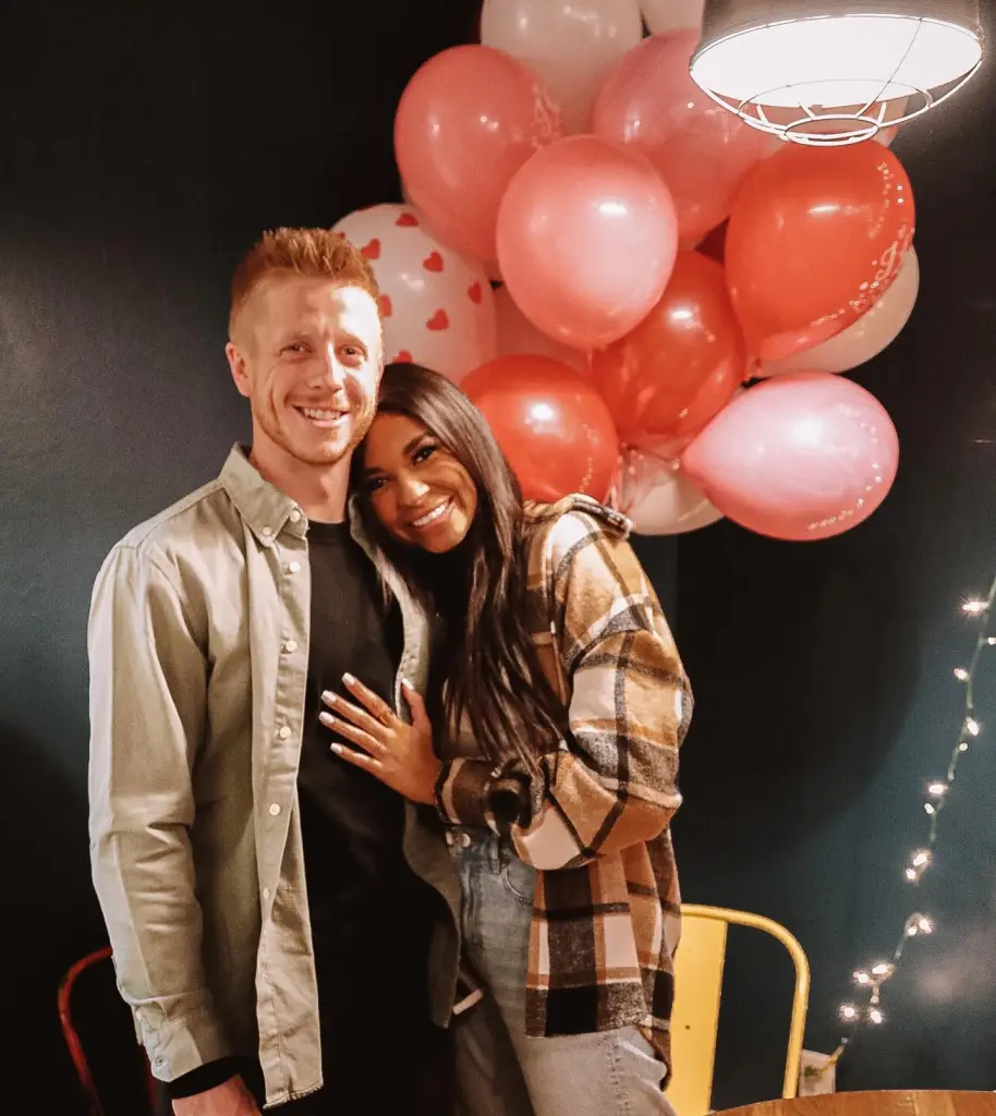 Layla Taylor and Clayton Wessel posing together in front of a cluster of red, pink, and white balloons.
