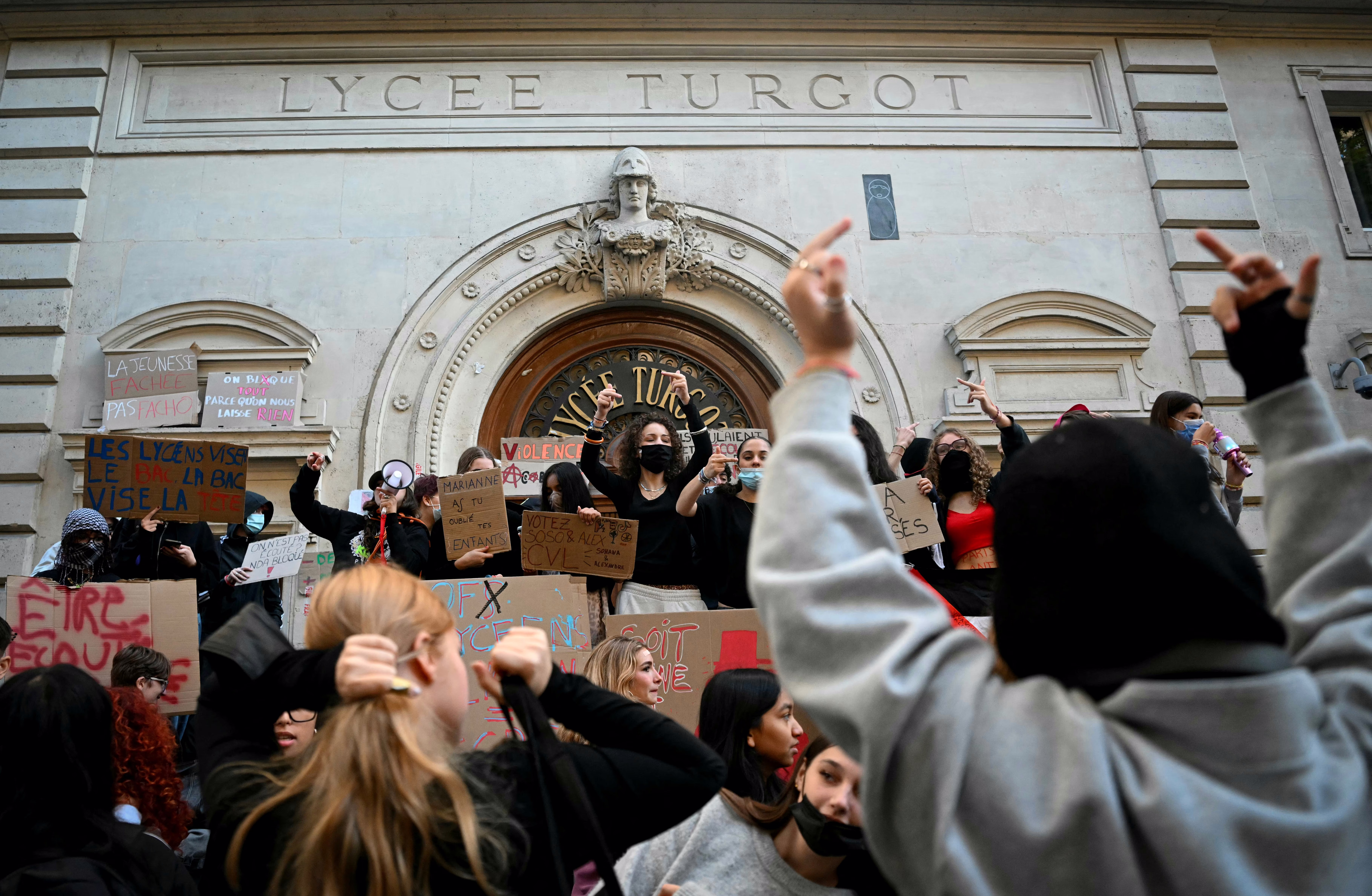 Protesting students gather and hold placards as they blockade part of a school.