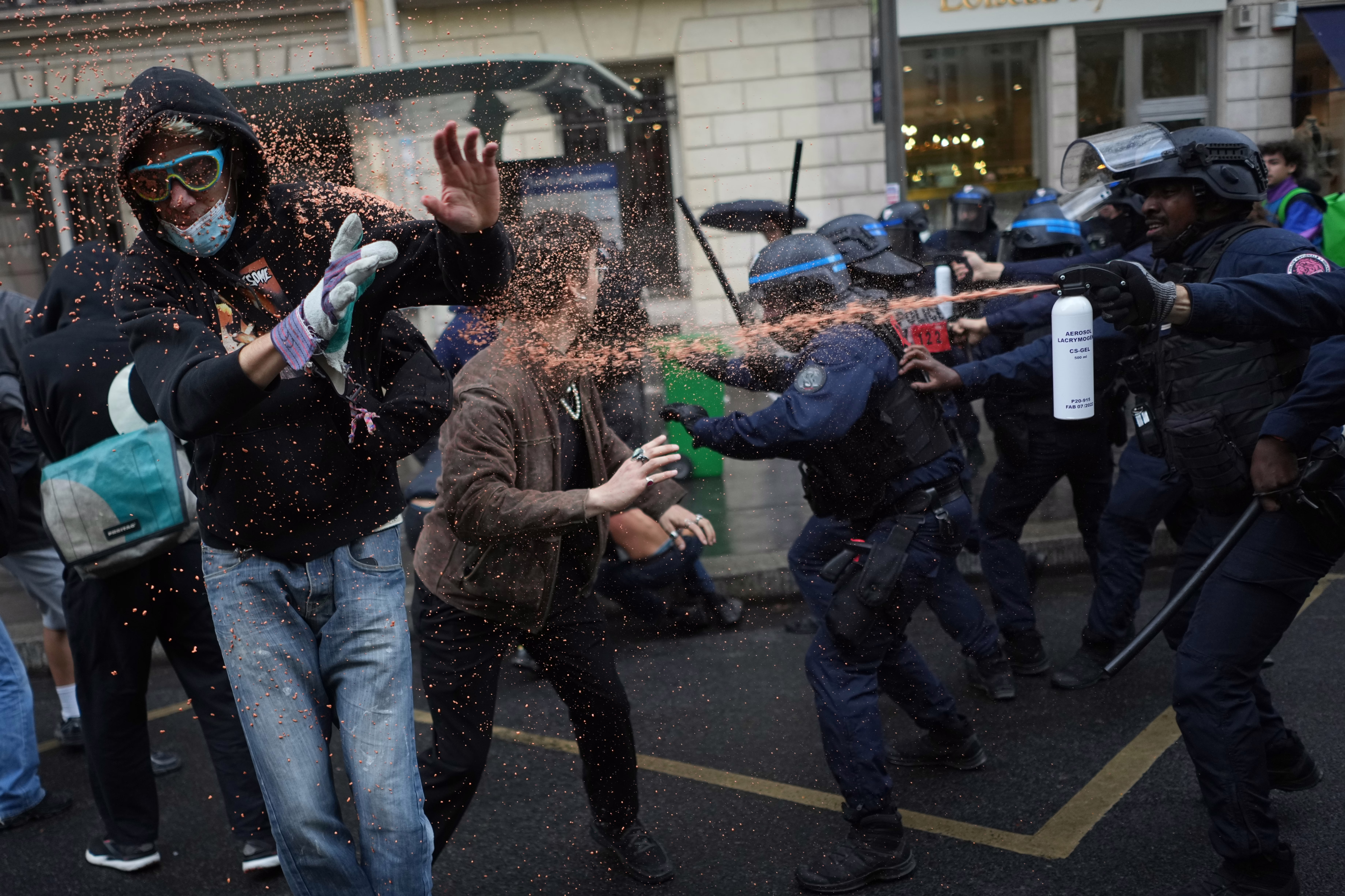 Police officers spray protesting students with pepper spray.