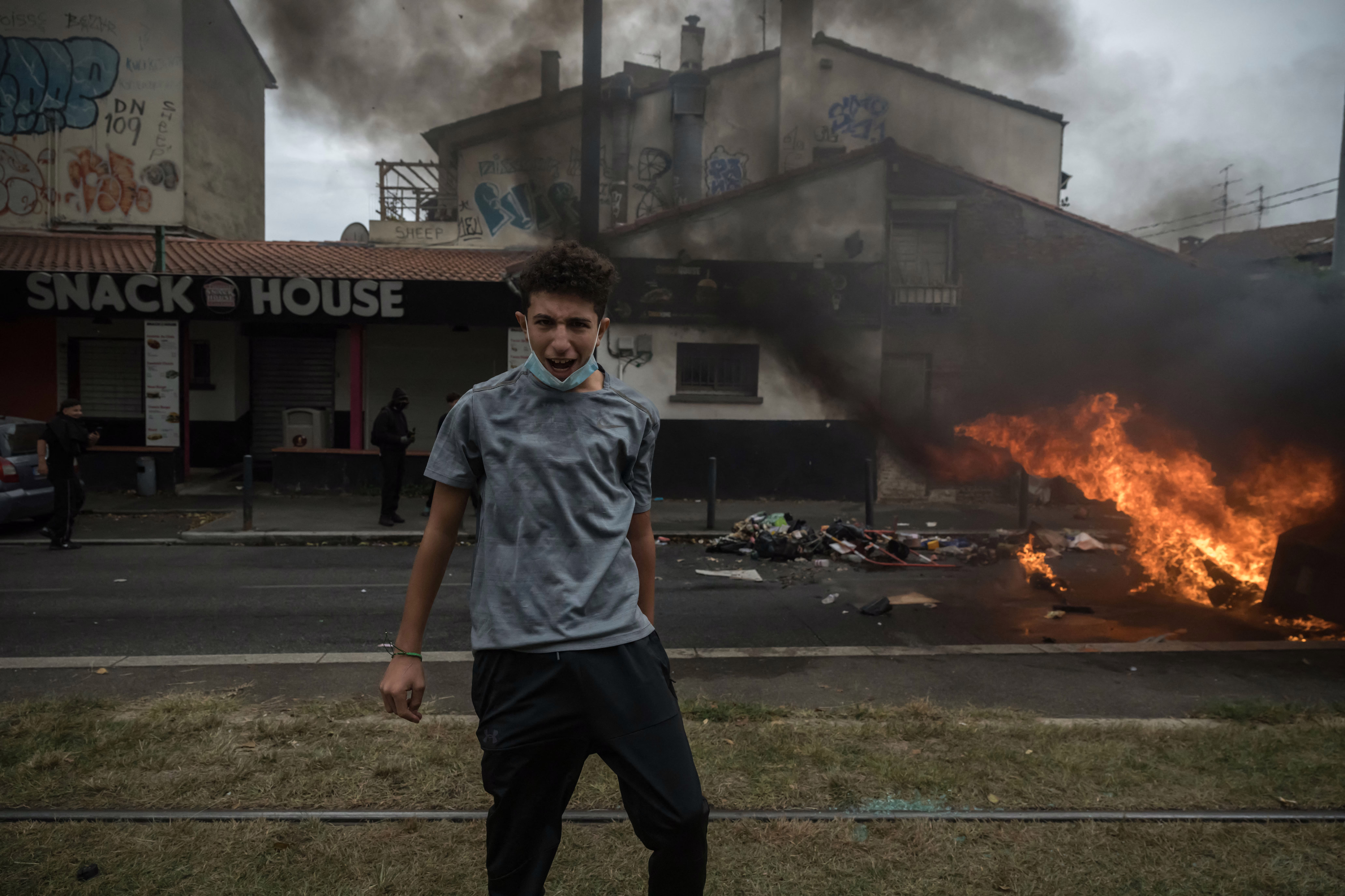 A protesting student reacts beside a burning barricade in a street.