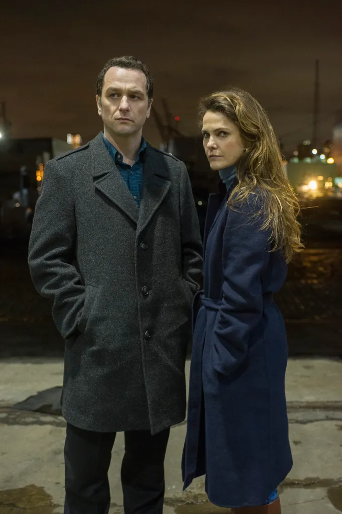 Philip and Elizabeth Jennings standing outdoors at night, wearing winter coats.
