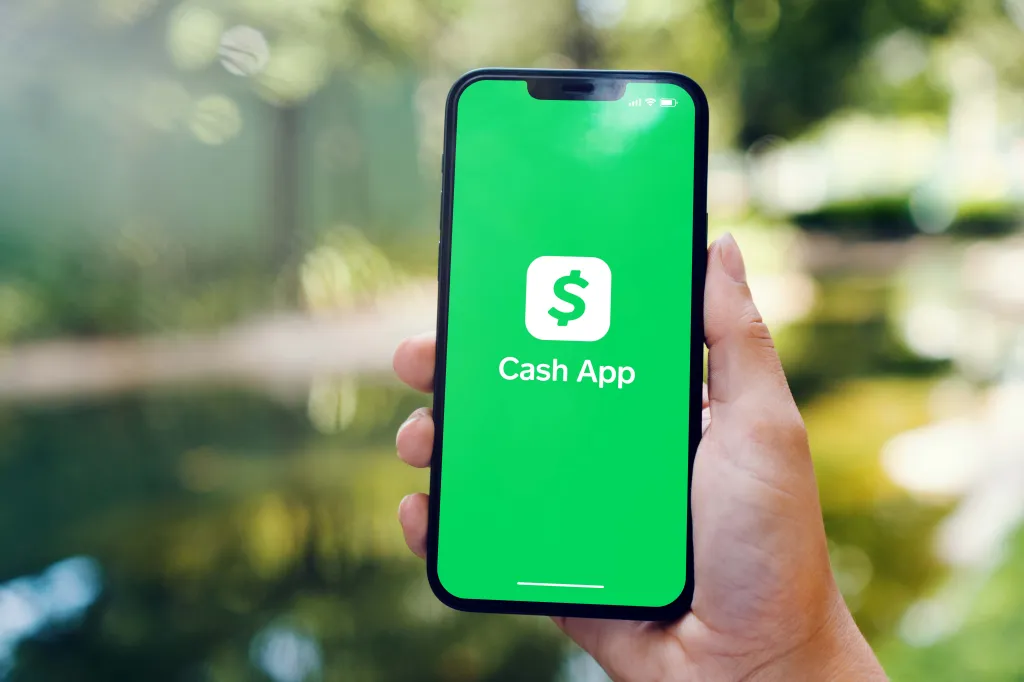A person holding a smartphone displaying the Cash App interface.