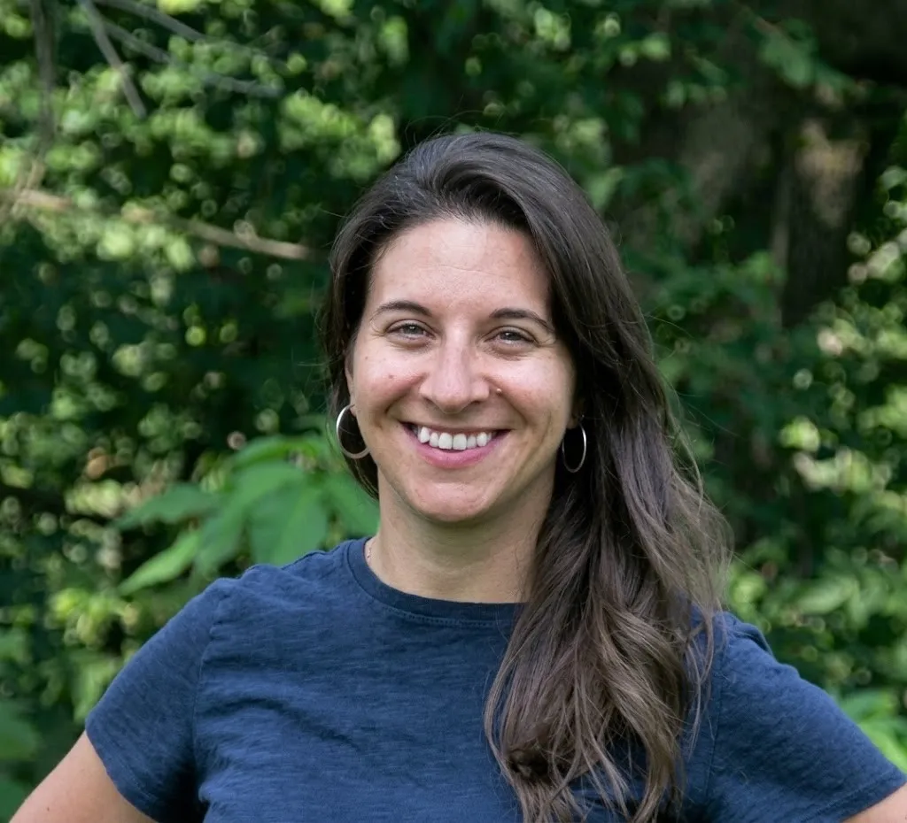 Stephanie Mickelson smiling against a green, leafy background.