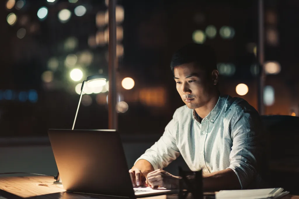 Asian businessman working on a laptop at his desk at night.