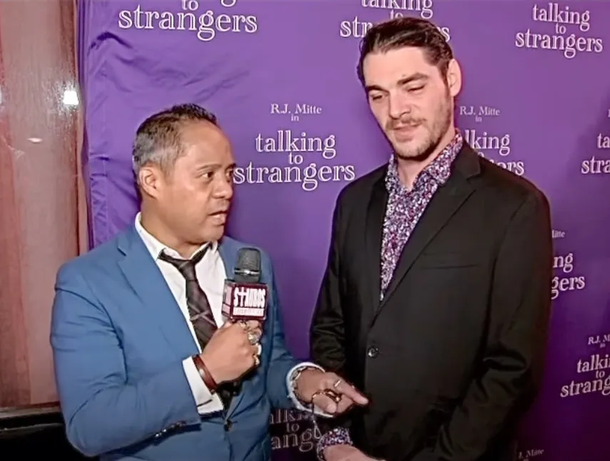 RJ Mitte being interviewed in front of a purple backdrop.
