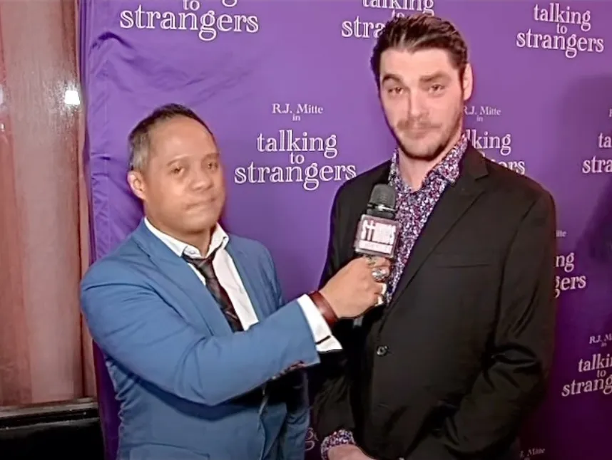 RJ Mitte being interviewed in front of a purple backdrop.