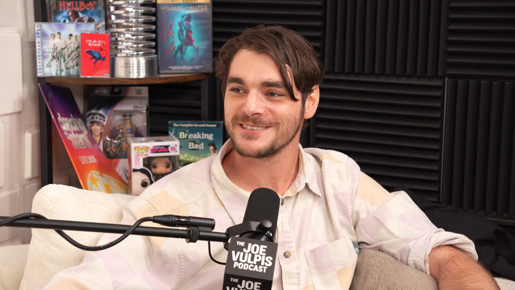 RJ Mitte sitting in front of a microphone on The Joe Vulpis Podcast.