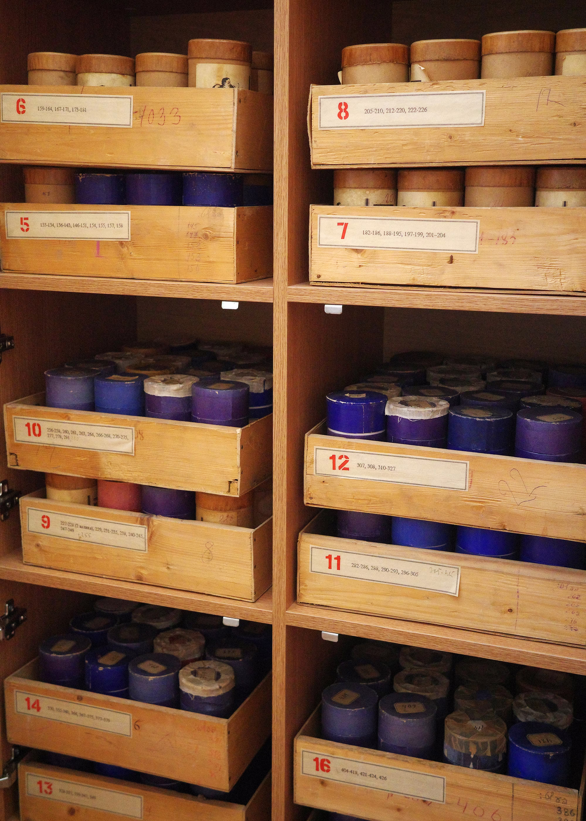 photo of wooden shelves stacked with numbered wooden crates, each holding dozens of cylindrical containers