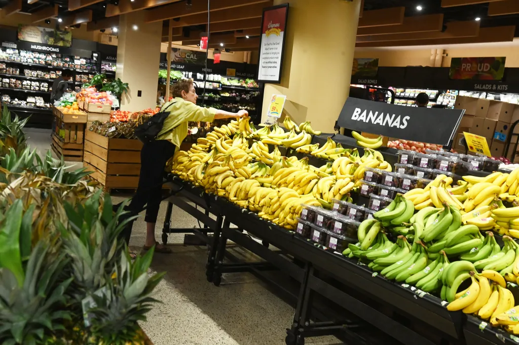A customer selects bananas at a grocery store display in New York.