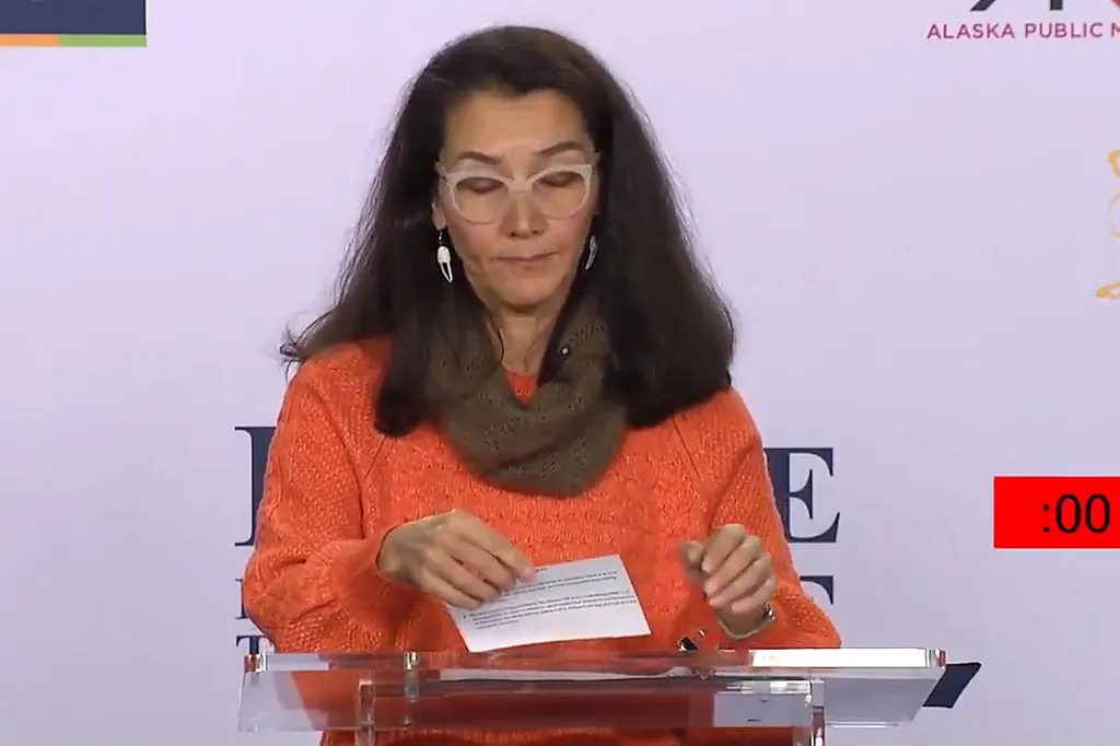 Mary Peltola looking down at notecards at a podium during a debate.