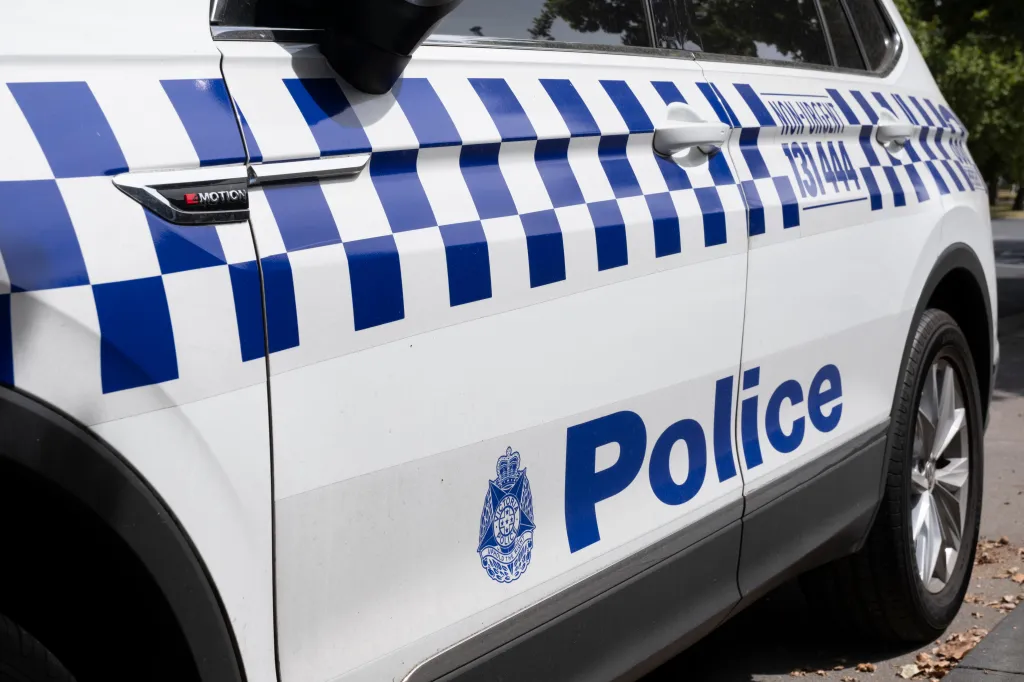 Side view of a Victoria Police car with distinctive blue and white checkerboard striping, symbols, and signs.