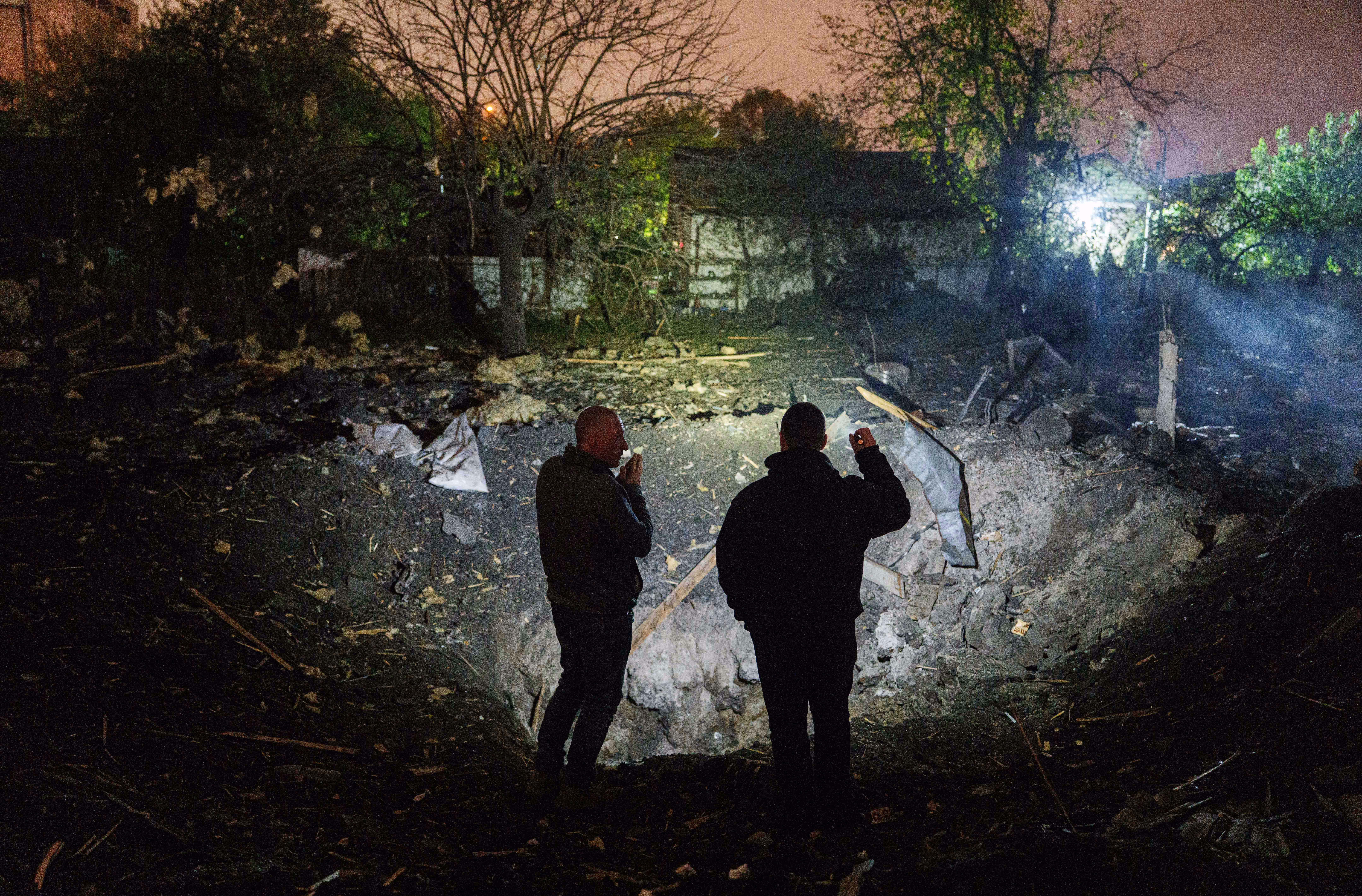 Two people look at a crater after a Russian missile strike in Ukraine.