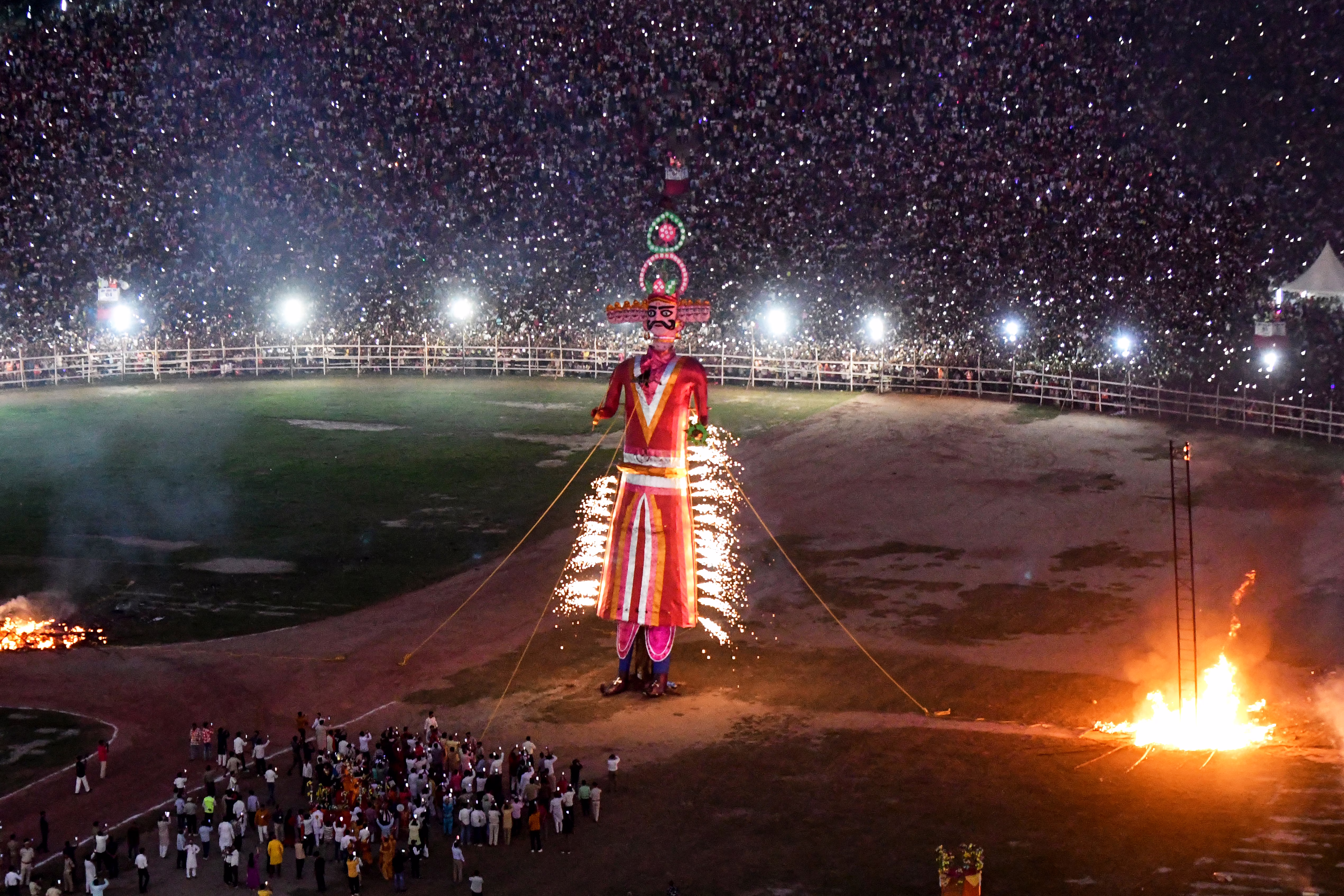 An effigy of a mythical demon king is set on fire in an arena full of spectators.